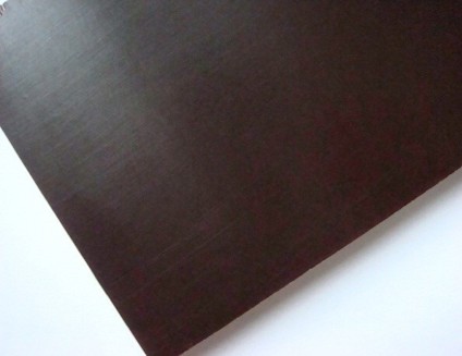 Mörkbrun, slät formplywoodskiva mot vit bakgrund, med subtila träådringar.