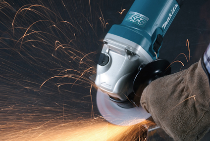 Vinkelslip i drift med gnistor som flyger, hålls av person i arbetshandske.