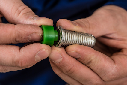 Händer monterar en grön distansbricka på en karmhylsa som en del av karminfästningen