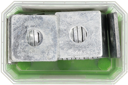 Metallblock staplade i en genomskinlig låda med grön botten.