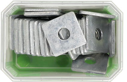 Metalliska fyrkantiga brickor med hål i mitten, staplade i en grön plastbehållare.