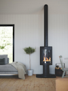 En modern svart kamin med glasfront och synliga lågor, placerad i ett ljust vardagsrum med parkettgolv och vita väggar.