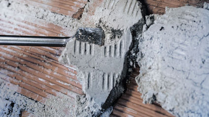 Närbild på en yta där murbruk appliceras med en murslev på tegelvägg.