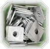 Fyrkantiga metallbrickor staplade i en transparent plastbehållare.